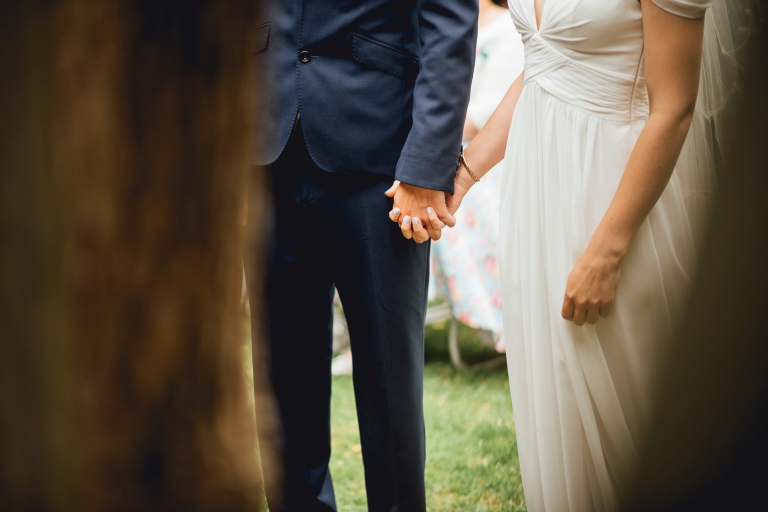close up of groom holding brides hand