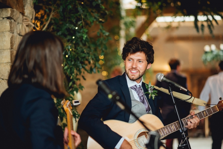 groomsman playing guitar for guests