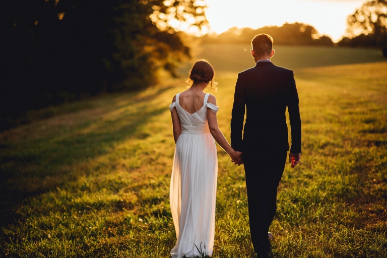 bride and groom holding hands walking away
